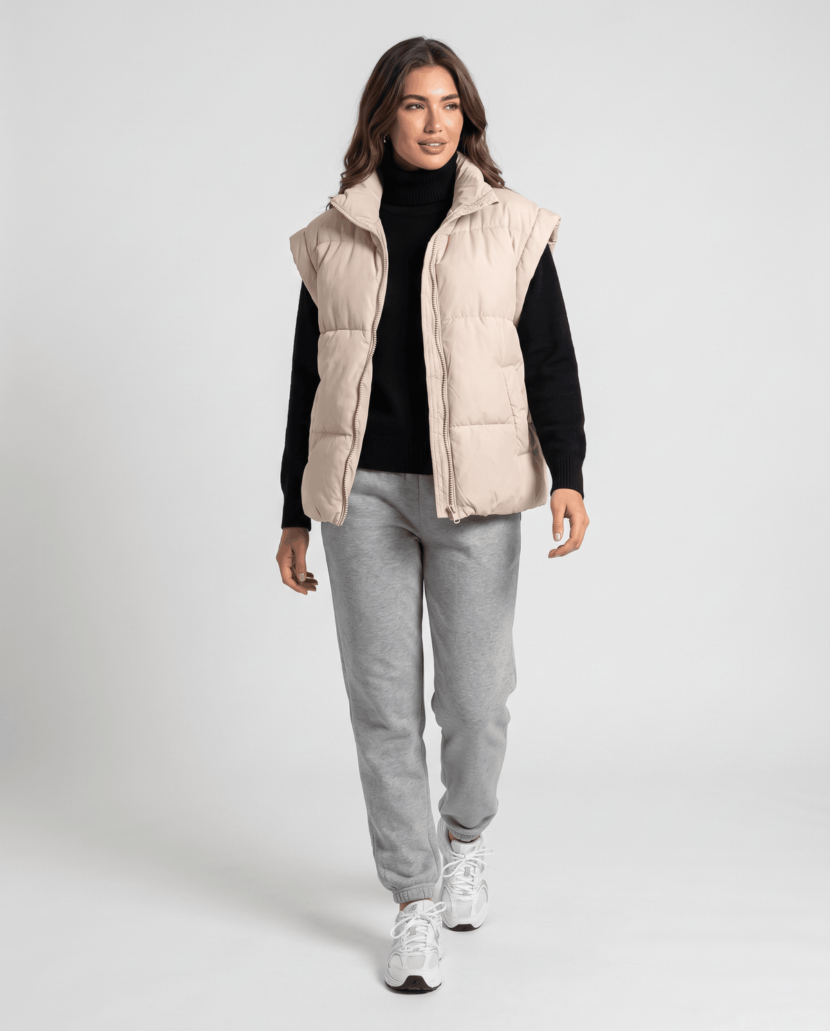 Full-length look with beige padded vest, black turtleneck and gray joggers
