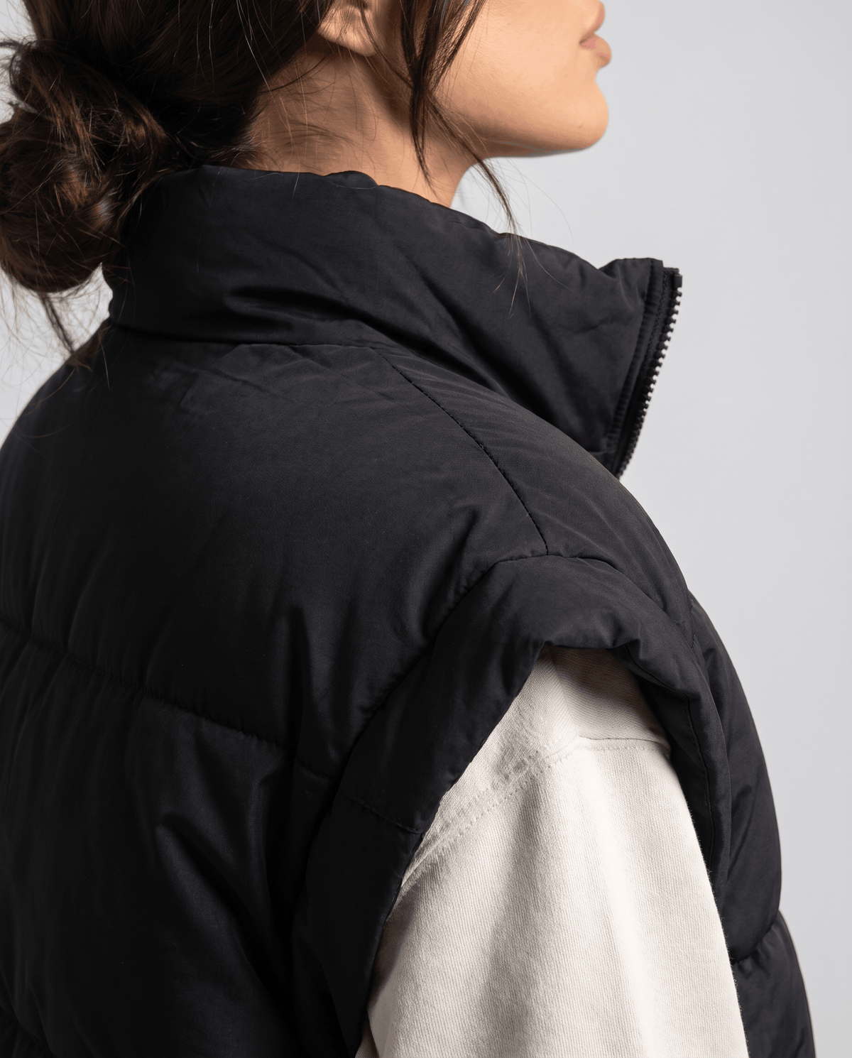 Close side view of black padded vest raised stand collar and shoulder