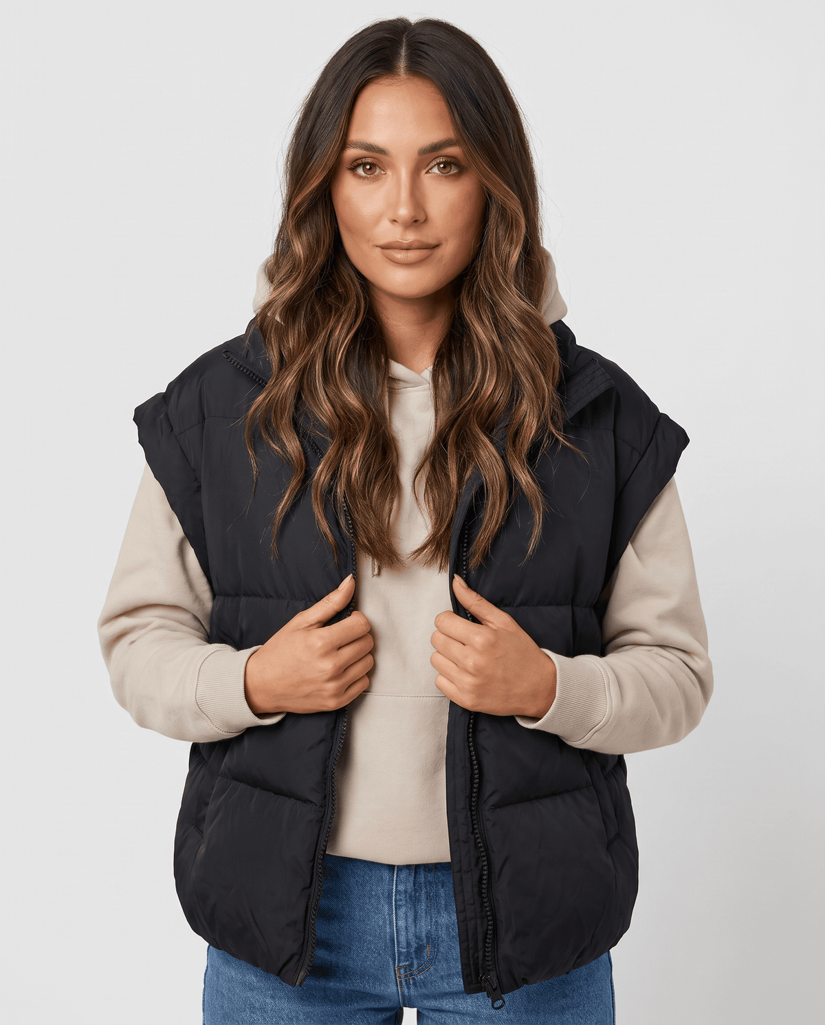 Women's black padded stand collar vest worn open over a beige sweater