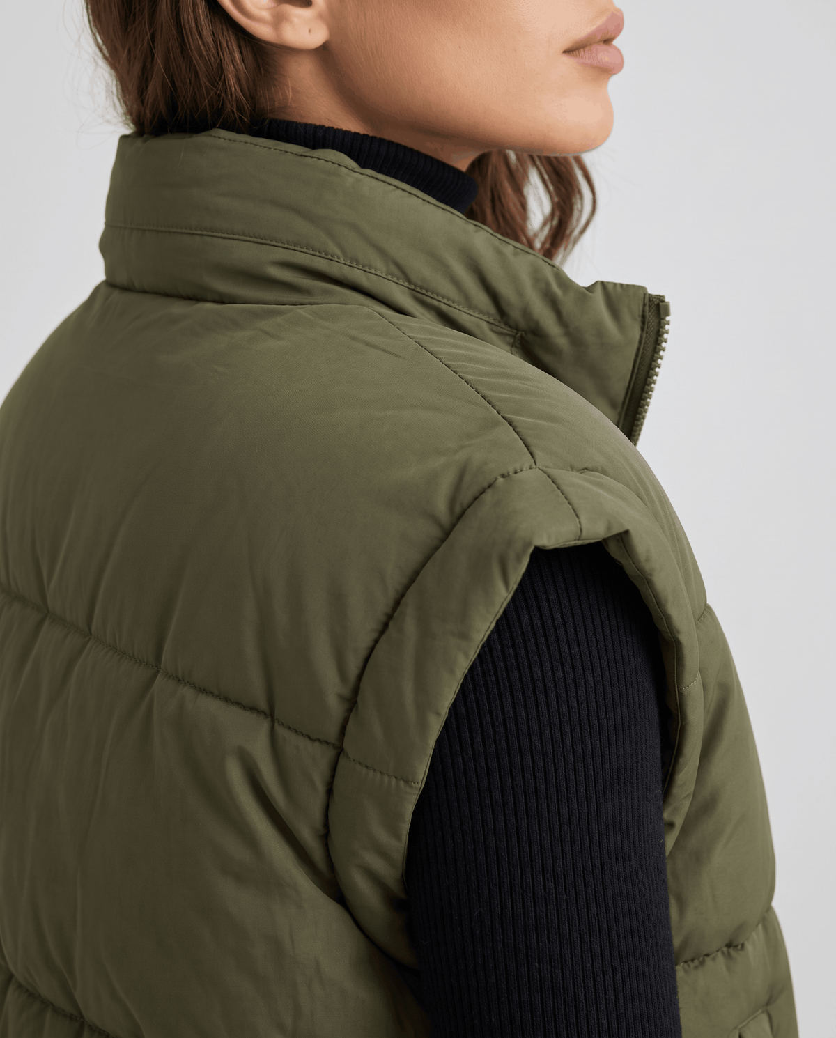 Close side view of green padded vest collar and sleeveless armhole