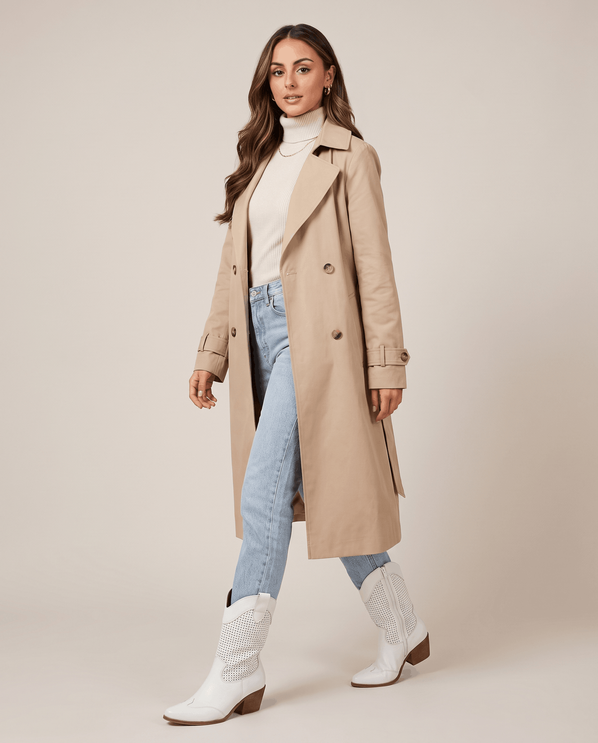 Woman in a beige trench coat and light-wash jeans wearing white western boots