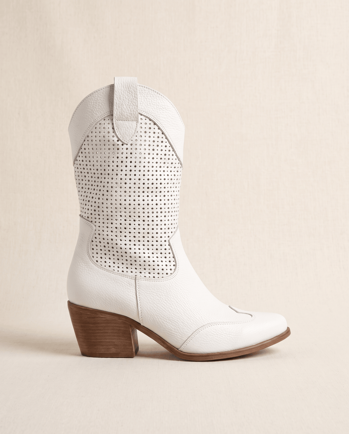 Single white western boot in side profile against a soft cream backdrop