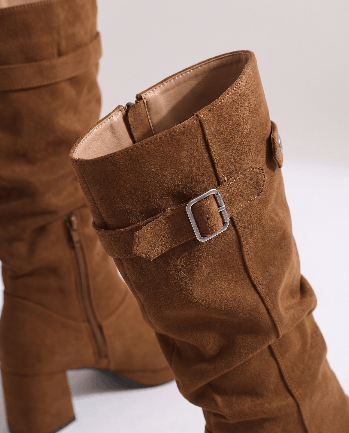 Close-up of the brown buckle strap, snap tab and soft brushed texture