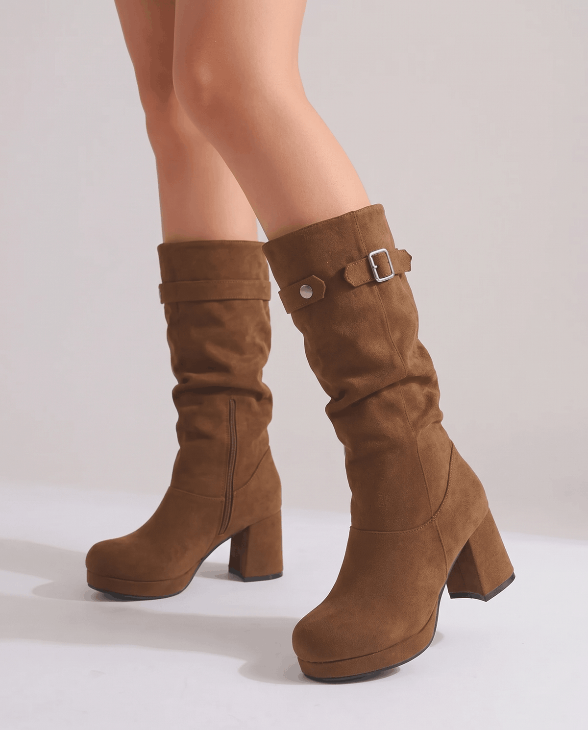 Woman with bare legs walking in brown mid-calf boots on a white floor