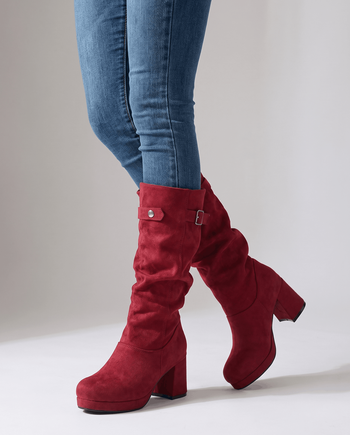 Woman in skinny blue jeans walking in red slouchy boots with a chunky heel