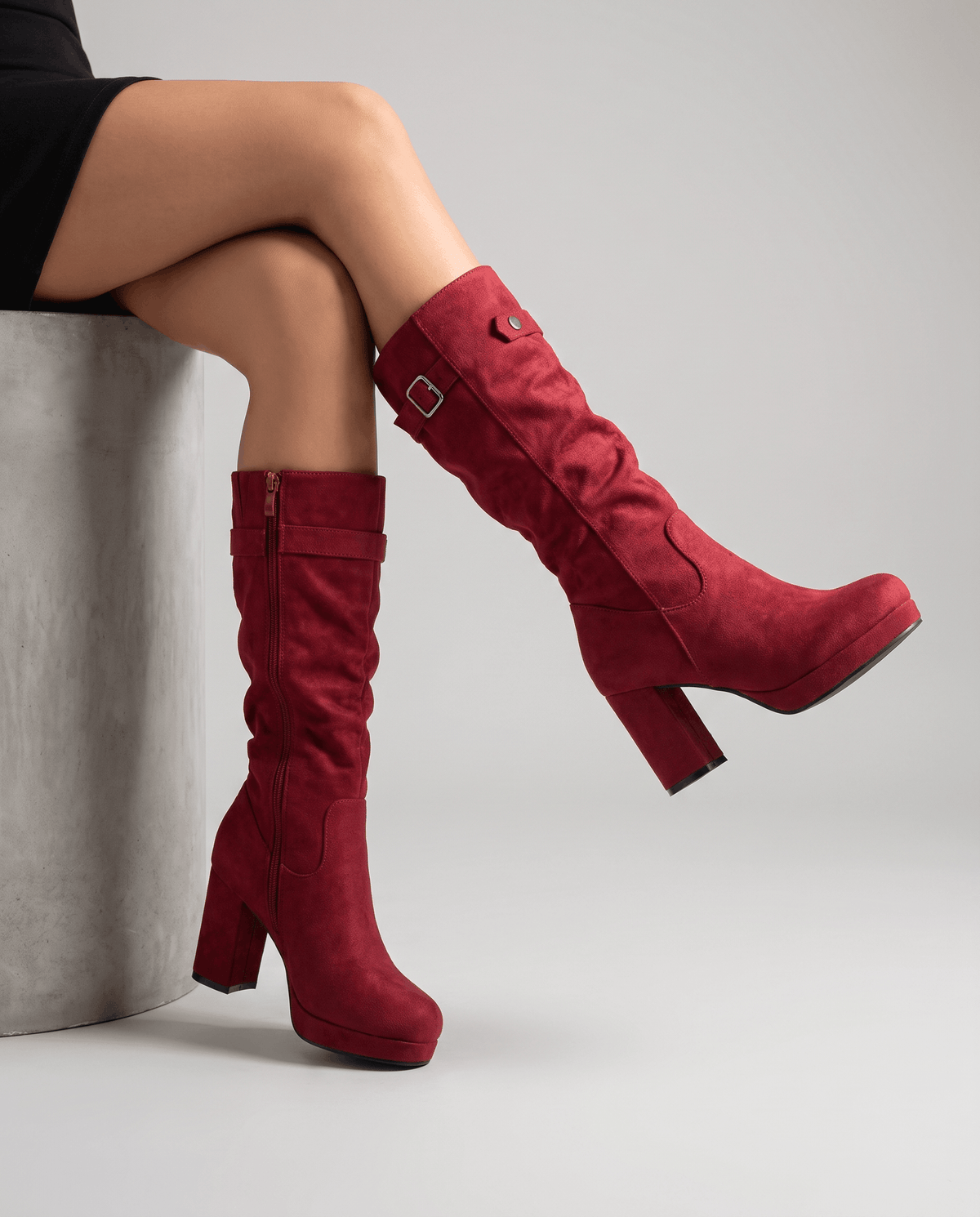 Seated woman with crossed legs wearing red boots, inside zip visible on one side