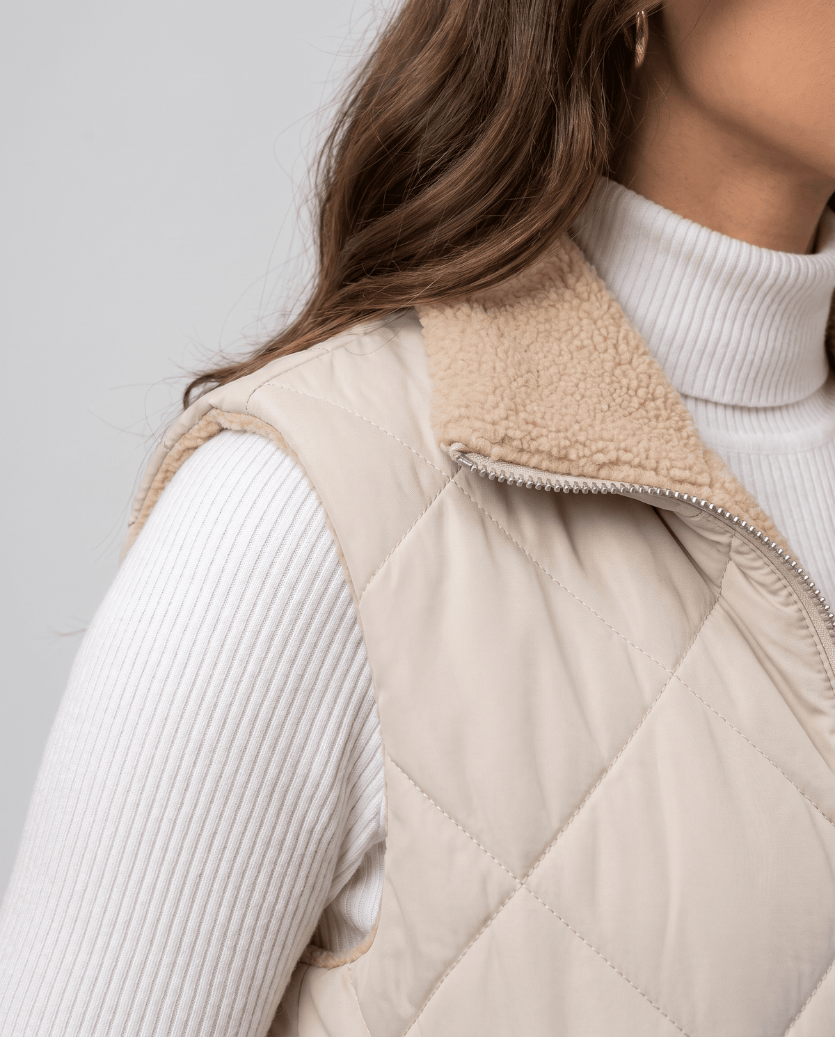 Side detail of light beige quilted vest collar and shoulder