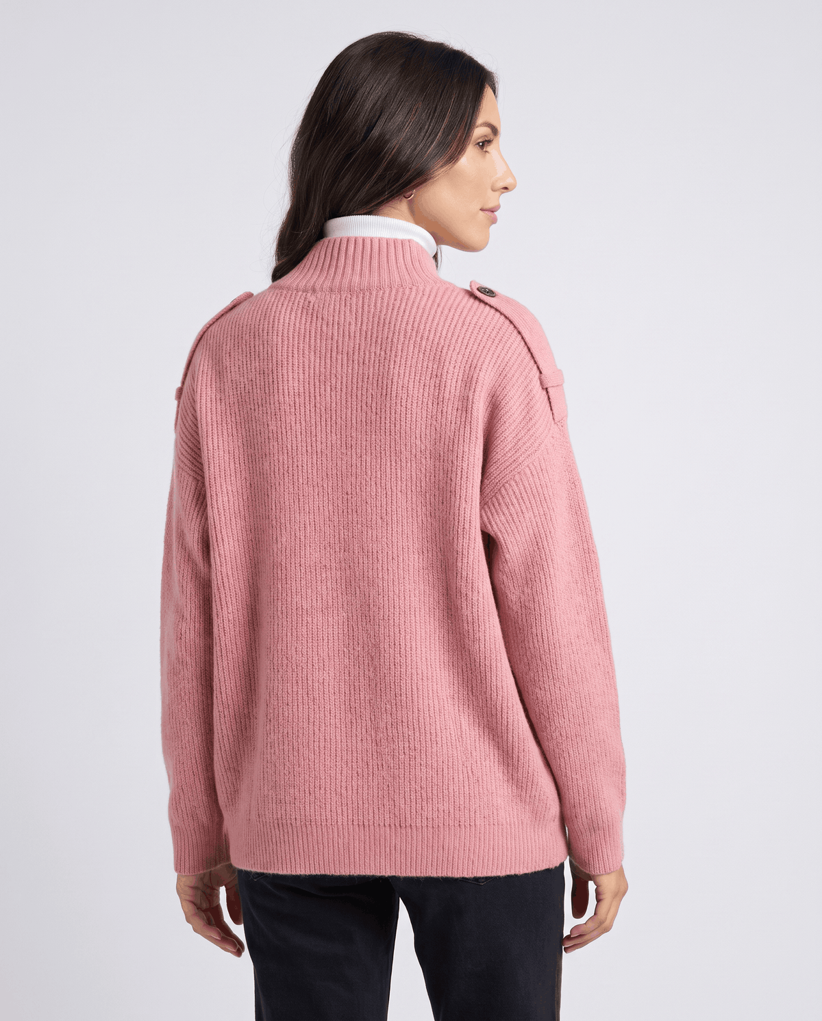 Back view of woman in pink ribbed knit cardigan with relaxed fit over a white turtleneck