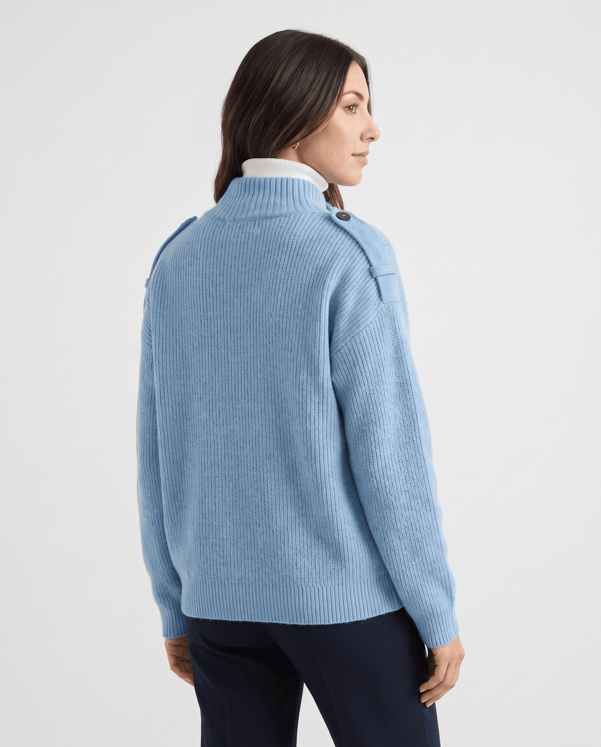 Back view of woman in sky blue ribbed knit cardigan with relaxed fit over a white turtleneck