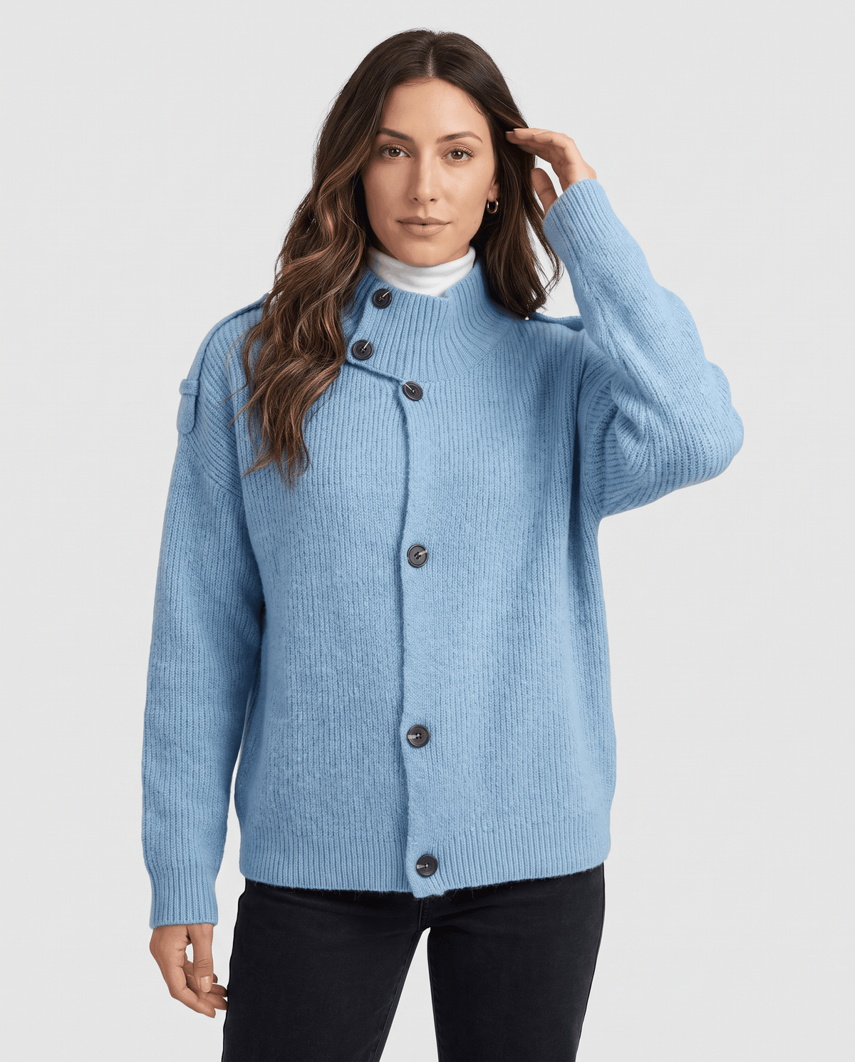 Woman wearing sky blue ribbed knit cardigan with stand collar and button front over a white turtleneck