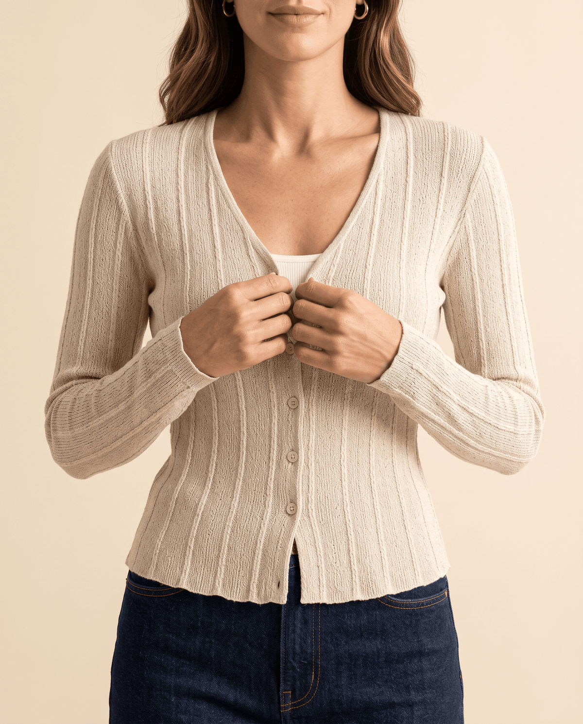 Cream ribbed cardigan with hands at the buttons showing the V neckline