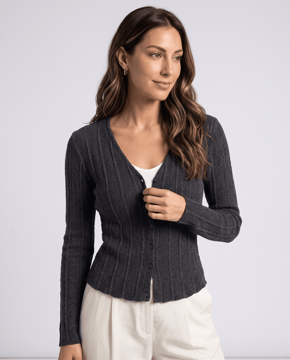 Women's dark gray ribbed V-neck cardigan with button front worn over a white top and cream trousers