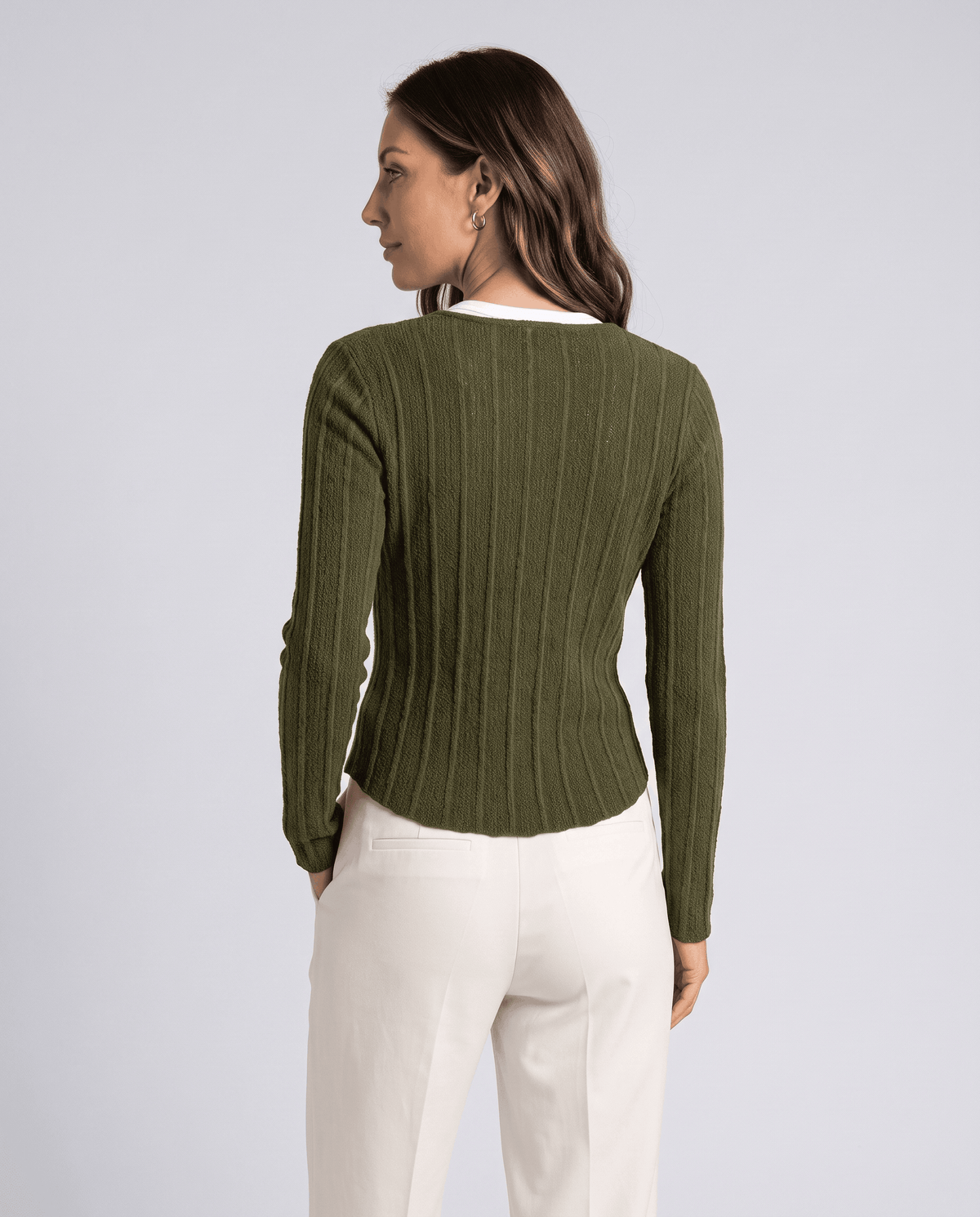Back view of green ribbed cardigan worn with cream trousers
