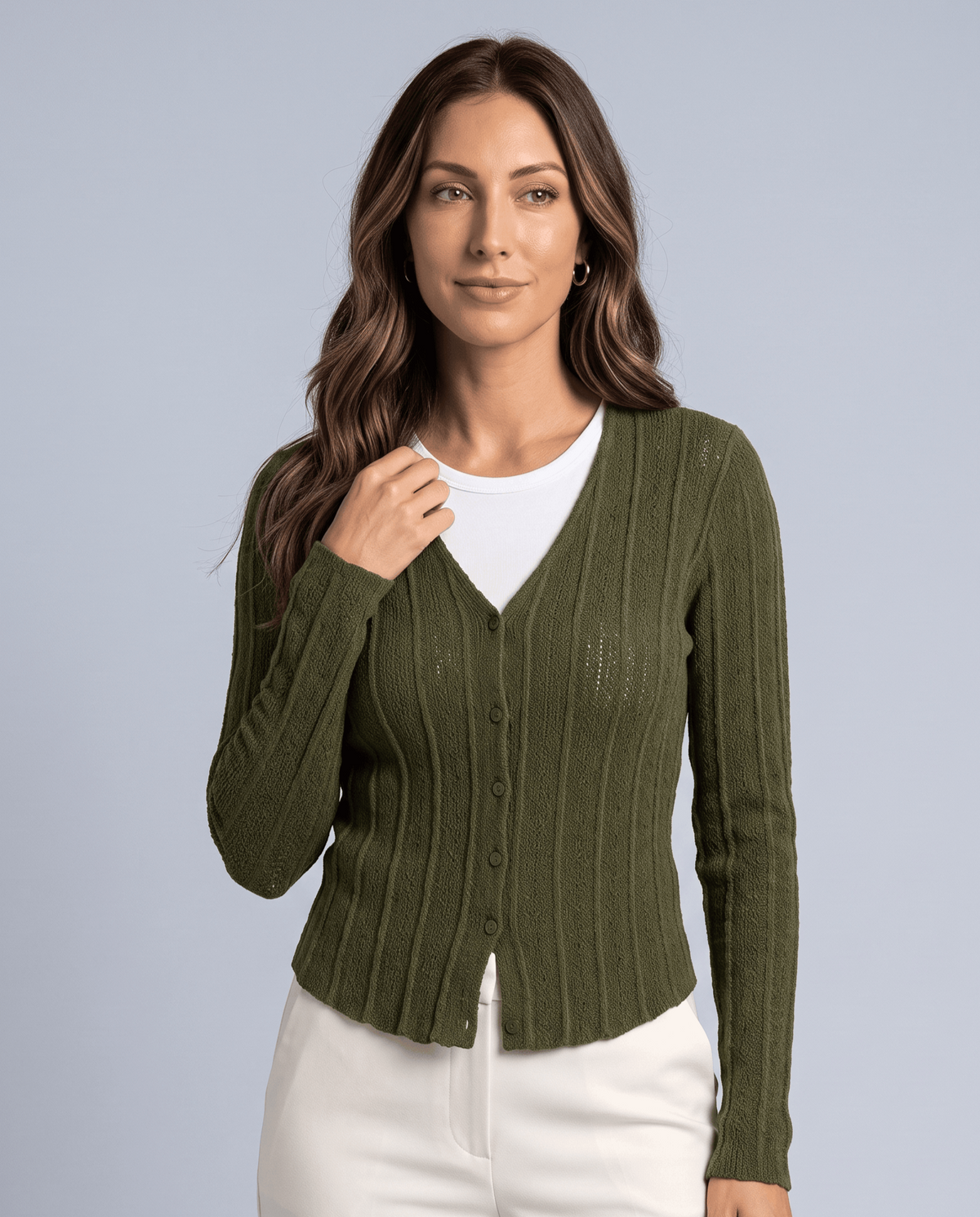 Women's green ribbed V-neck cardigan with button front worn over a white top and cream trousers