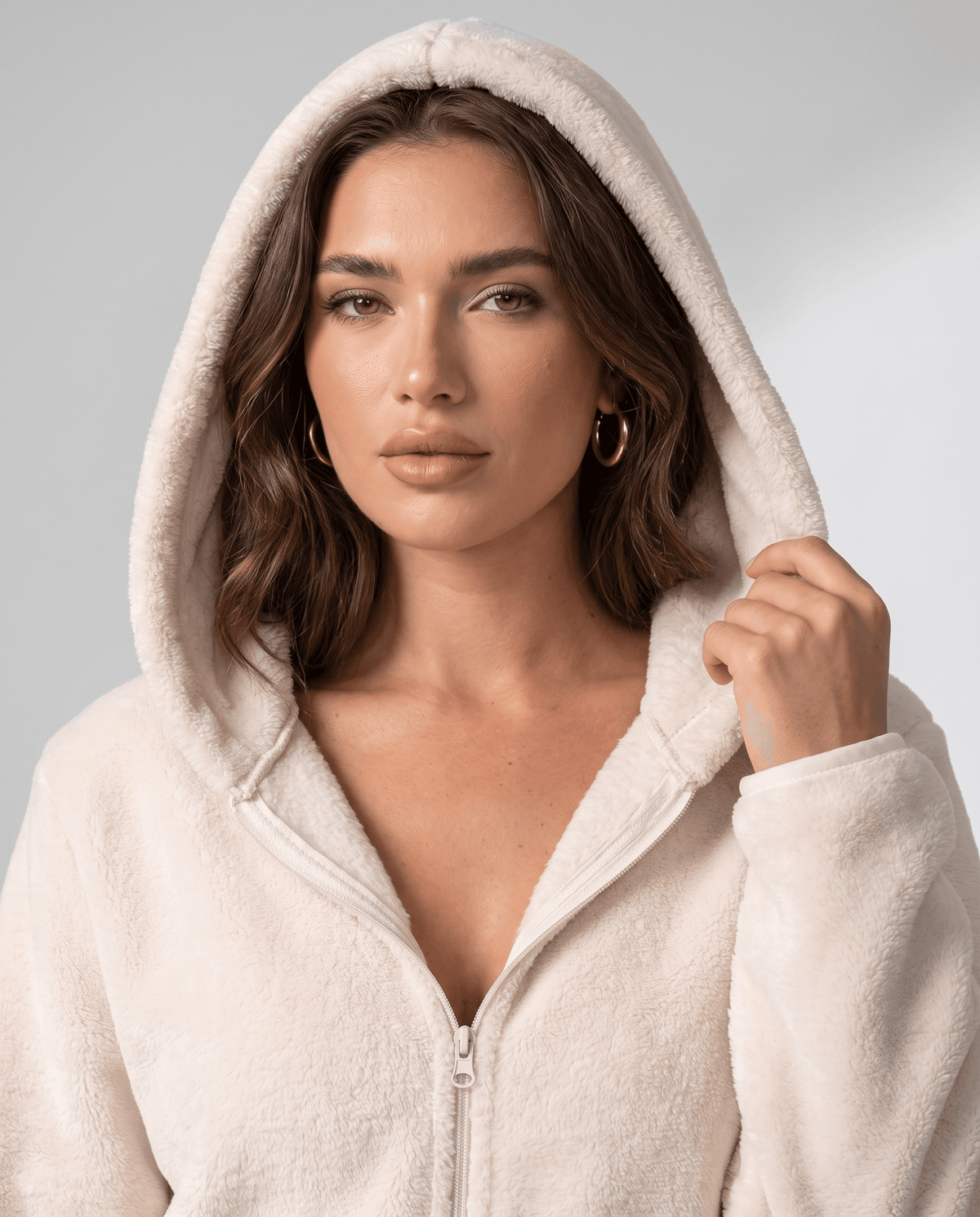 Cream sherpa hoodie with the hood up and a hand holding the hood edge