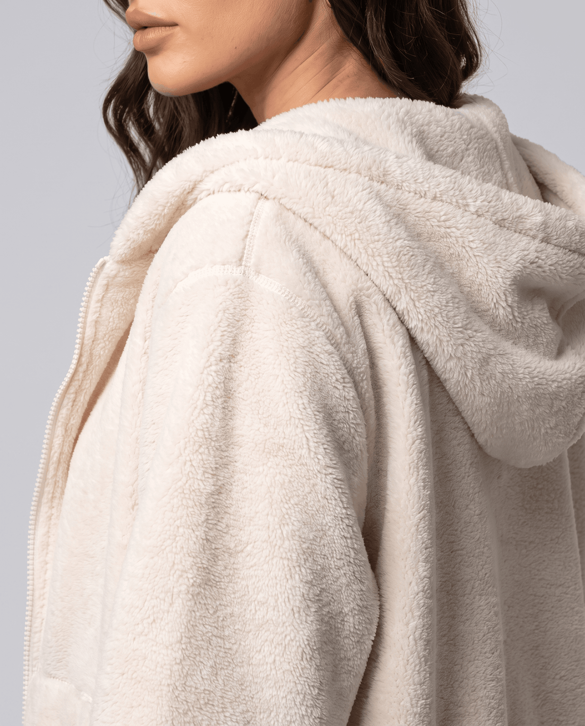 Cream sherpa hoodie from the side showing the hood, zip and sleeve