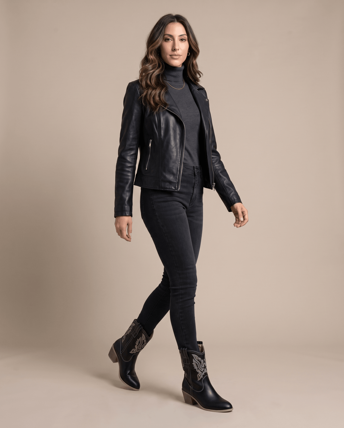 Woman in a black moto jacket and black skinny jeans wearing black western boots