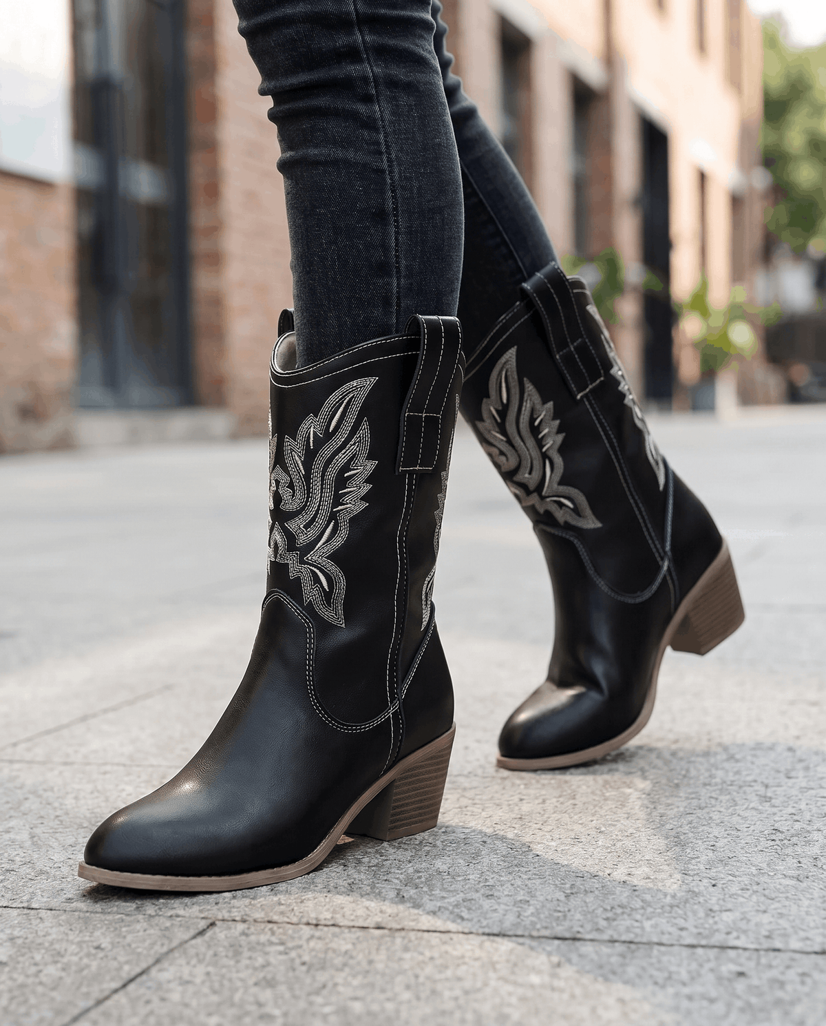 Black short boots worn walking on a city street with tucked dark jeans