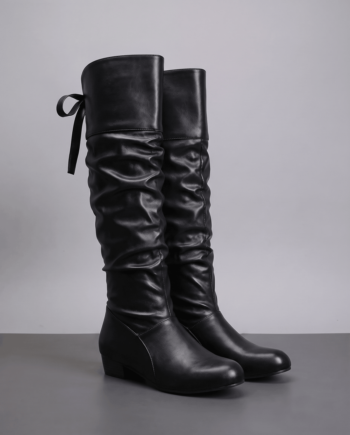 Leather-look slouch knee-high boots in black with a bow tie at the back of the cuff