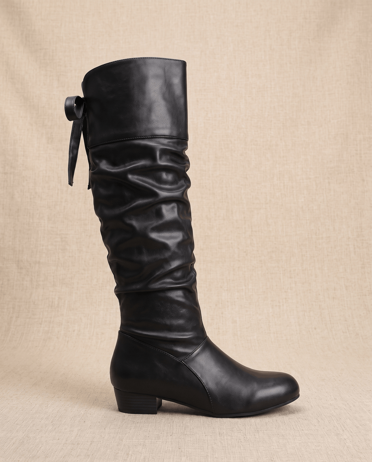 Single black boot in side profile with the ribbon tie and low heel