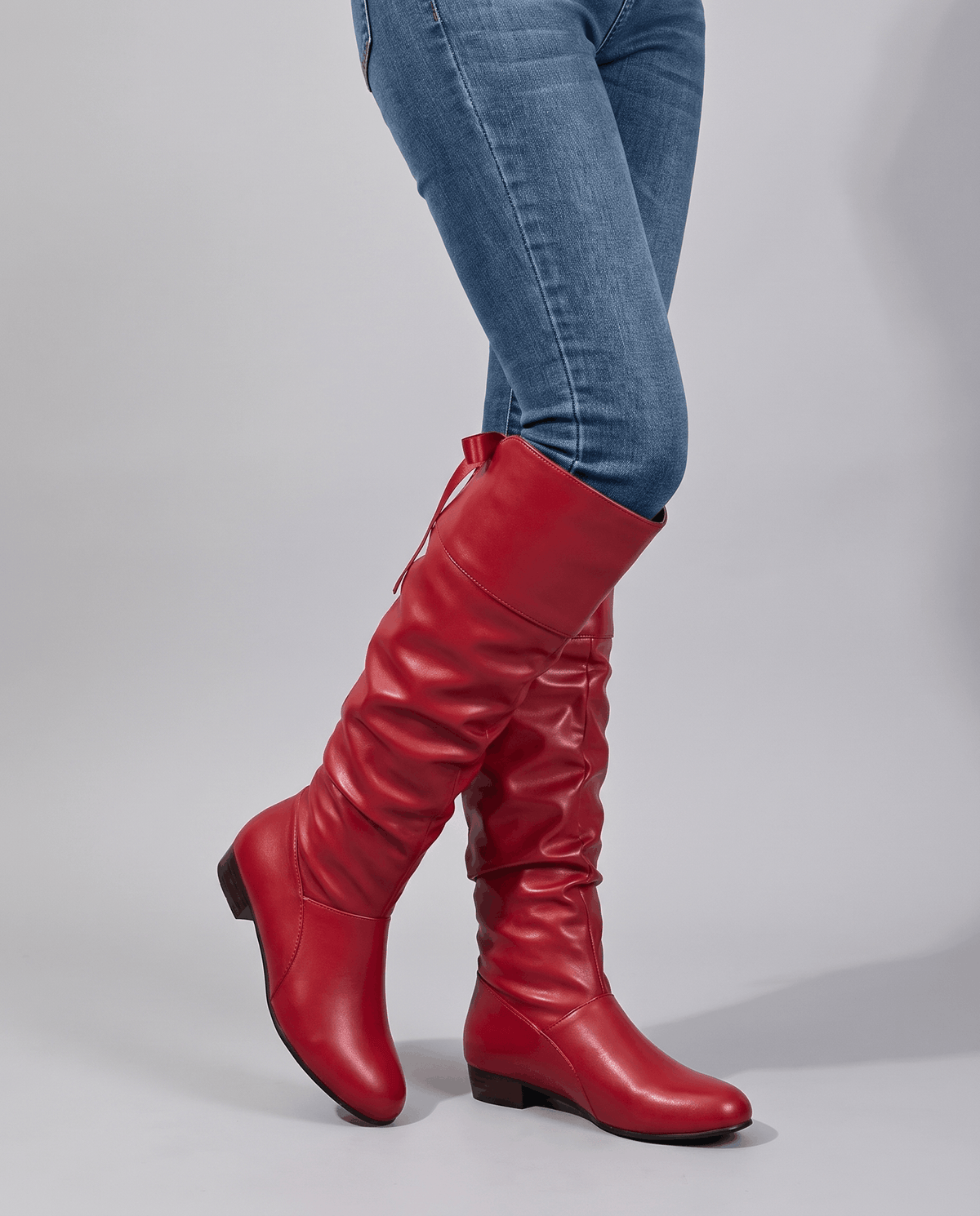 Woman in blue skinny jeans walking in red slouch boots