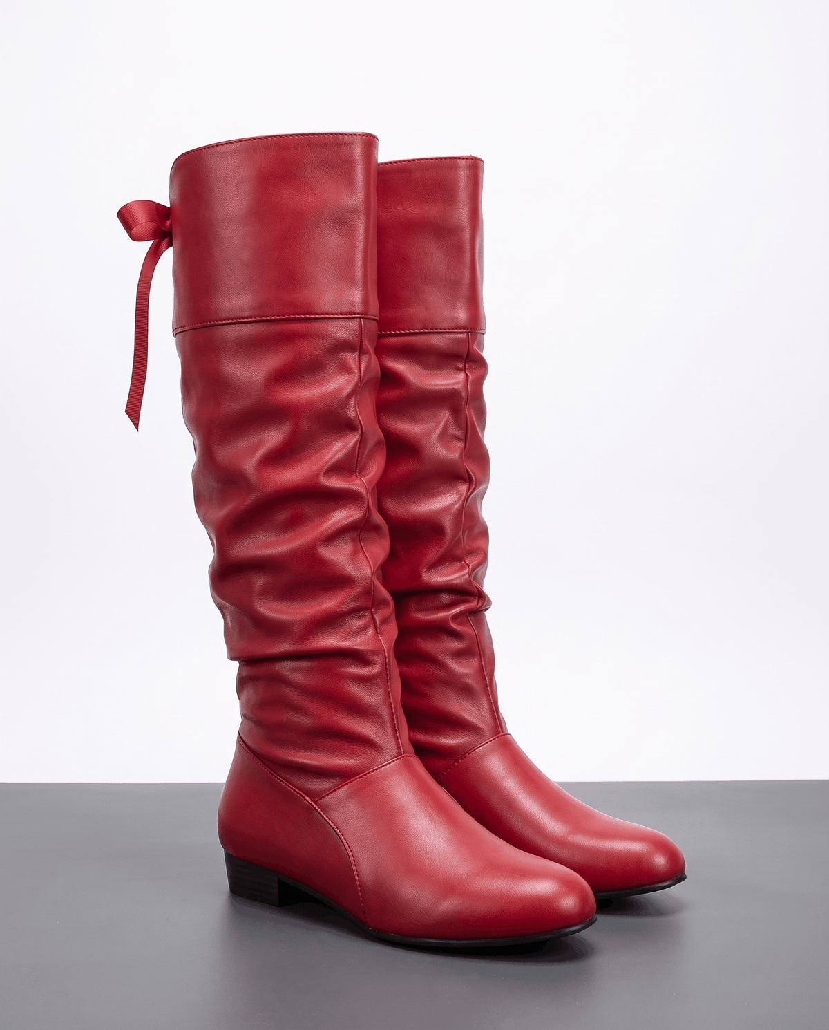 Red pair on a gray floor showing the ruched shaft and back ribbon tie