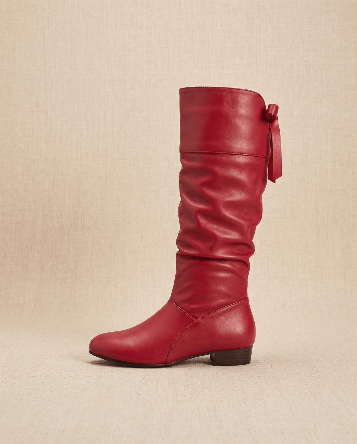 Single red boot in side profile with the bow tie and low heel