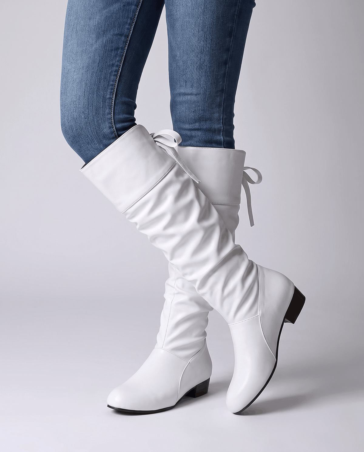 Woman in blue jeans walking in white slouch boots with back ties
