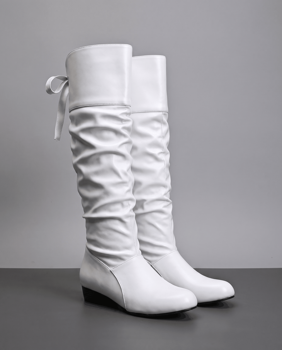 White pair on a dark floor with ribbon ties at the back of the cuff