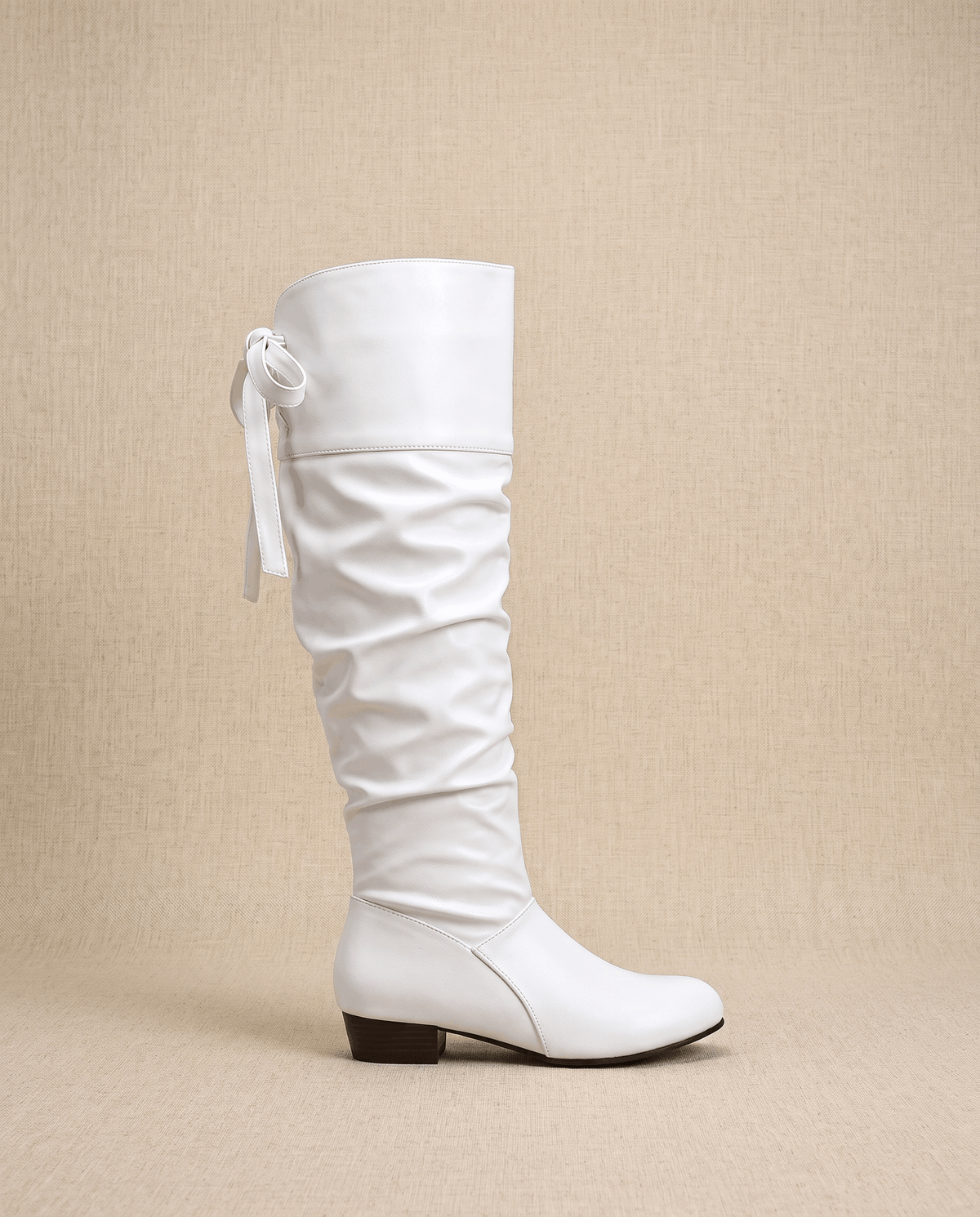Single white boot in side profile showing the bow tie and stacked heel