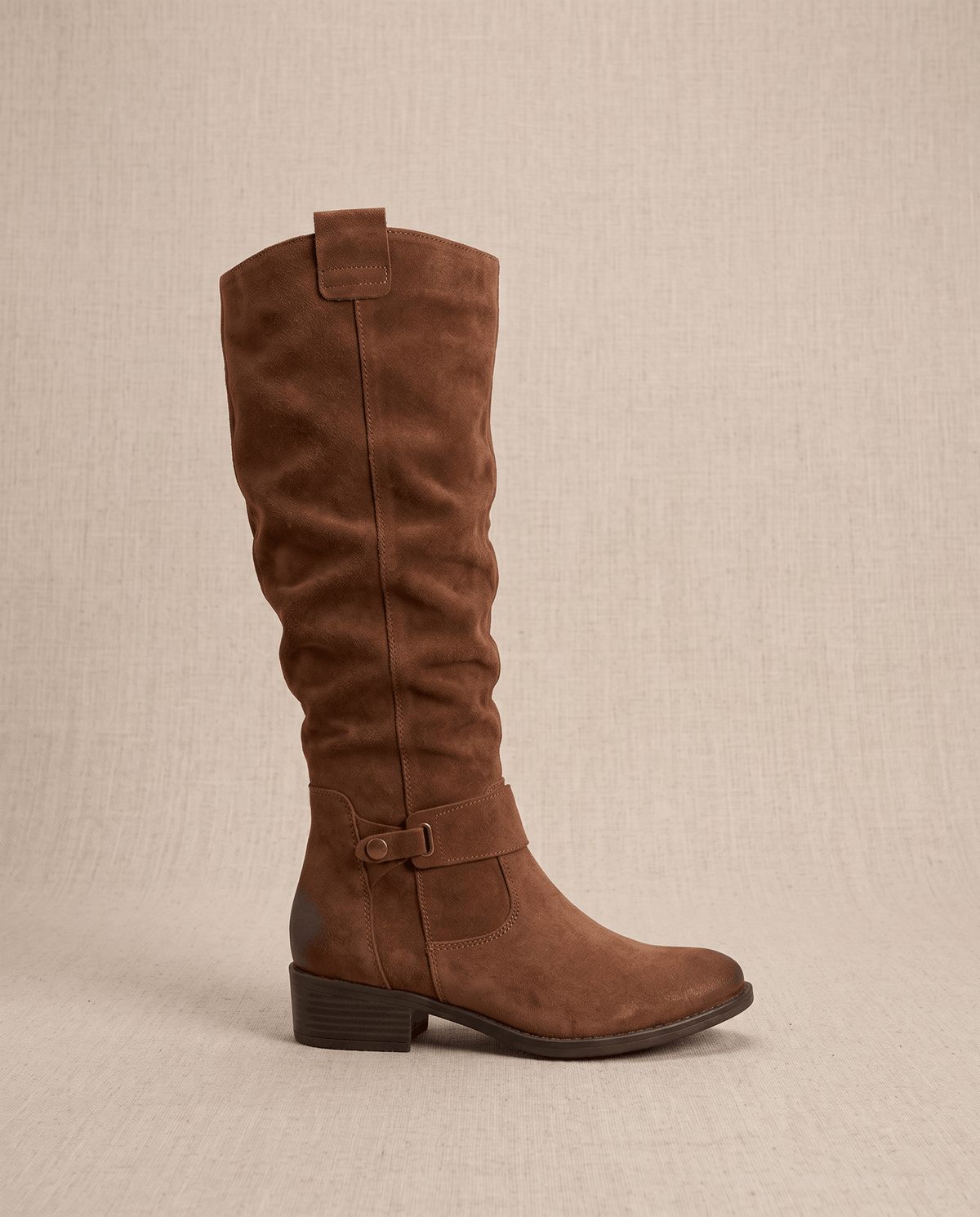 Single brown boot in side profile showing the pull tab, buckle strap and heel