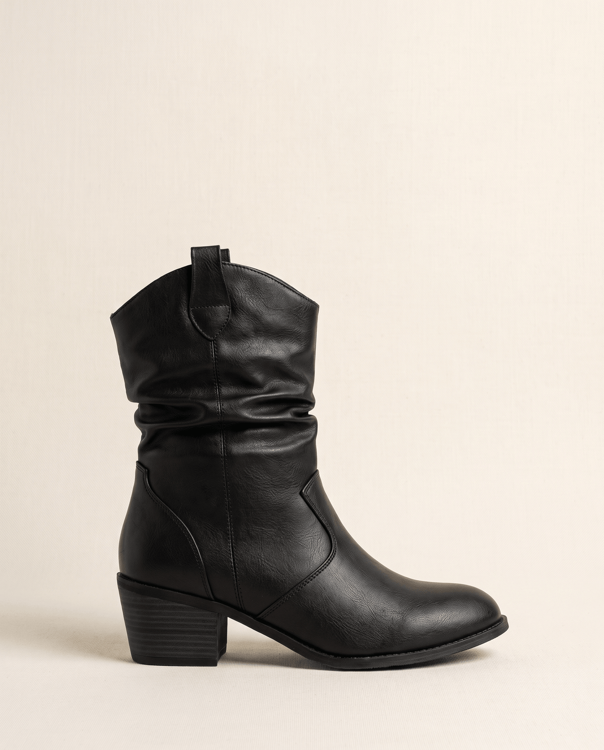 Single black boot in side profile against a soft cream backdrop