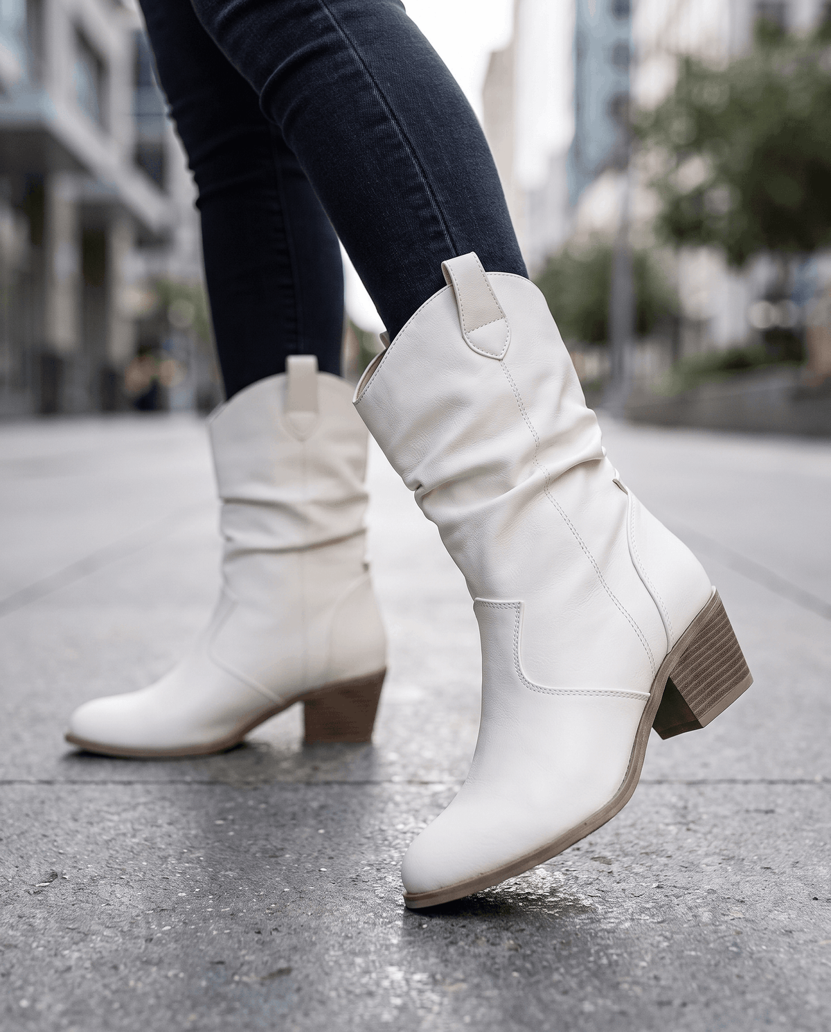 White western boots worn walking on a city sidewalk with black jeans