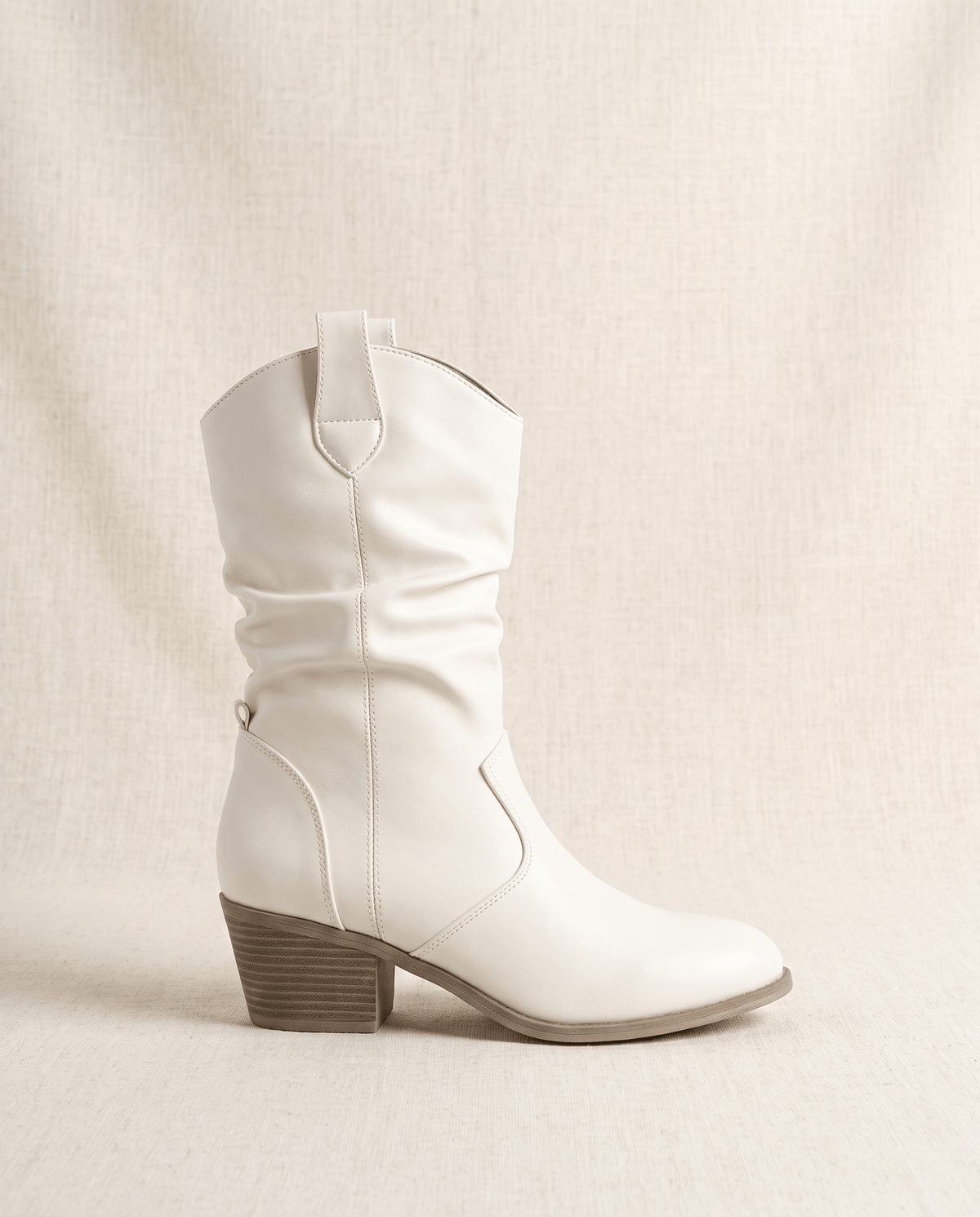Single white western boot in side profile showing the almond toe and pull tab