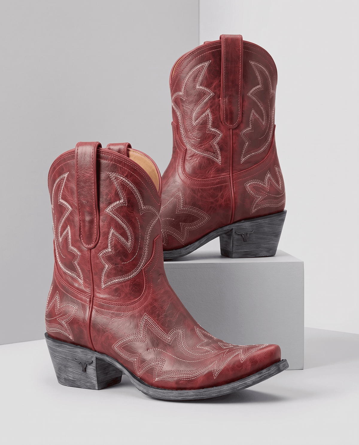 Red distressed western boots displayed on a white pedestal