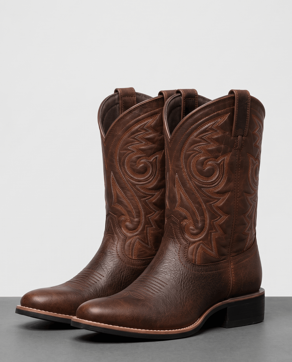 Pair of brown square-toe leather cowboy boots with tonal embroidery and stacked heels