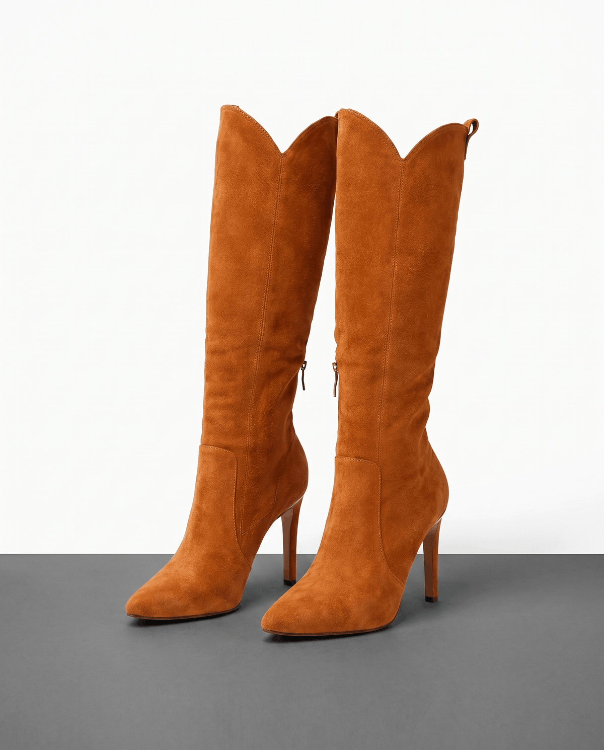 Camel suede knee-high boots with a pointed toe, slim stiletto heel, close-cut shaft, and side zip closure.