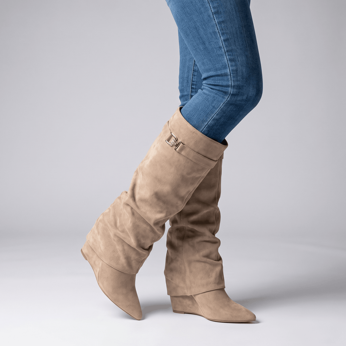 Woman wearing taupe suede fold-over knee-high boots with blue jeans.