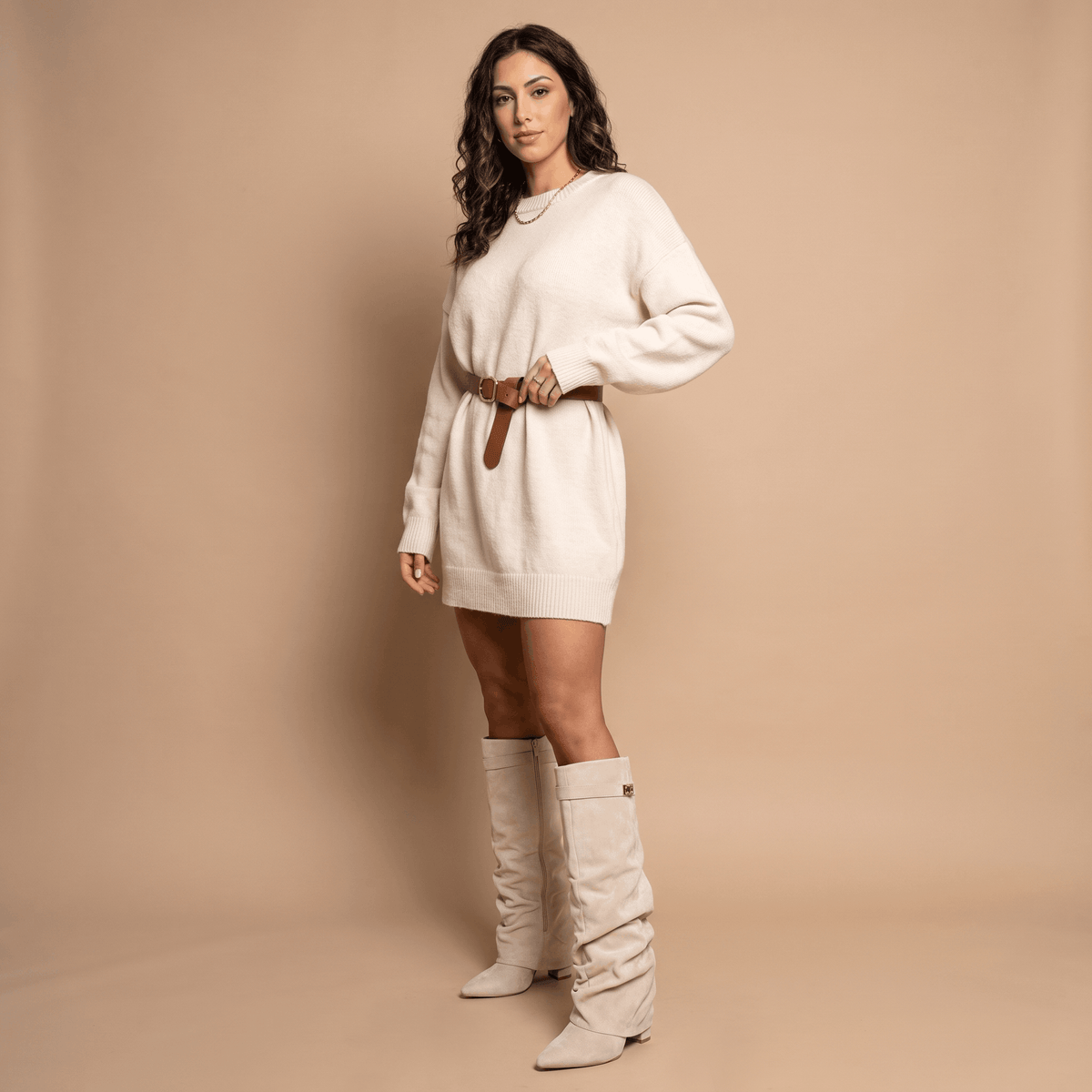 Woman wearing beige suede knee-high boots with a white outfit.