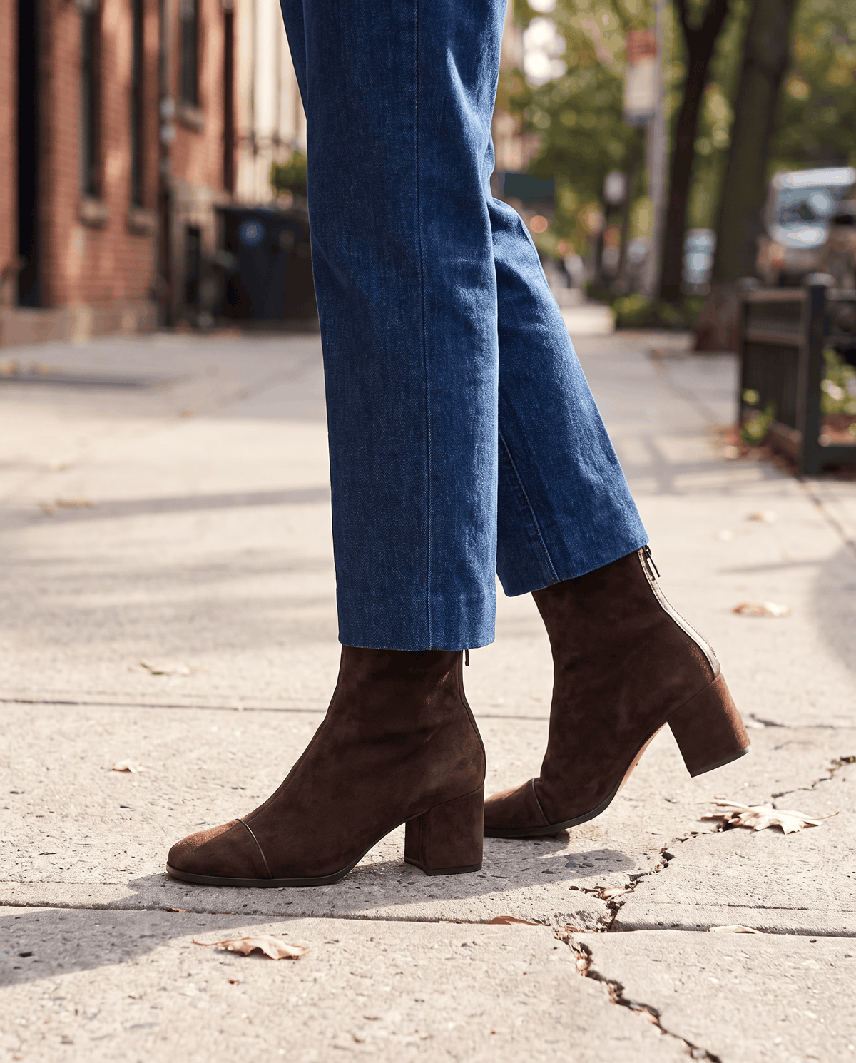 Brown suede ankle boots worn with straight-leg jeans on a street