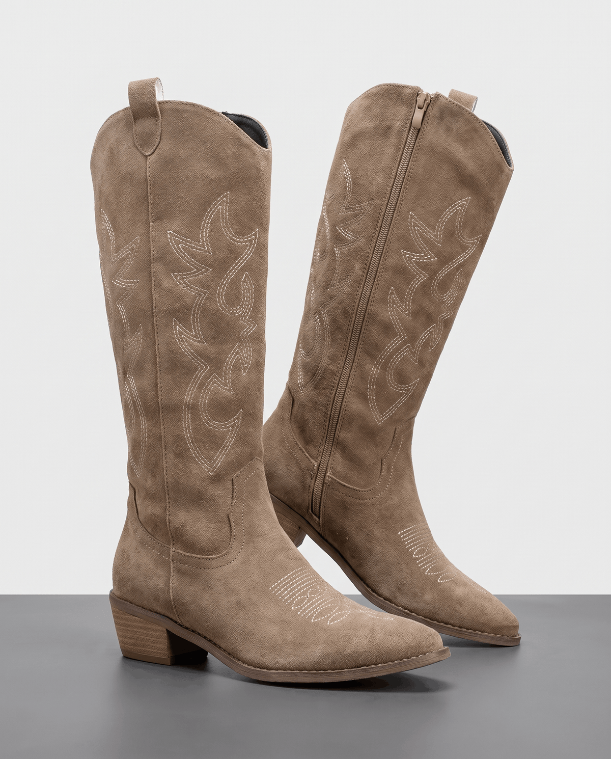 Pair of beige suede-look knee-high cowboy boots with tonal embroidery and stacked heels