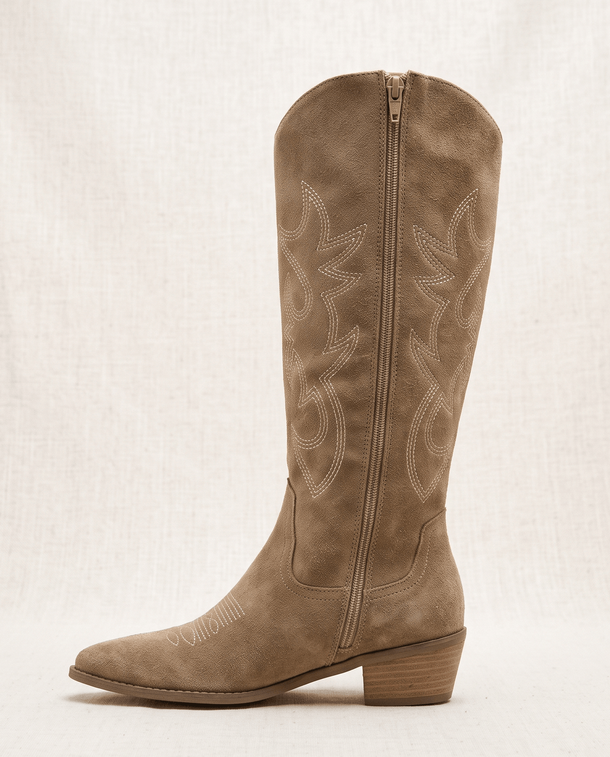 Side profile of a single beige western boot showing the full-length inside zip