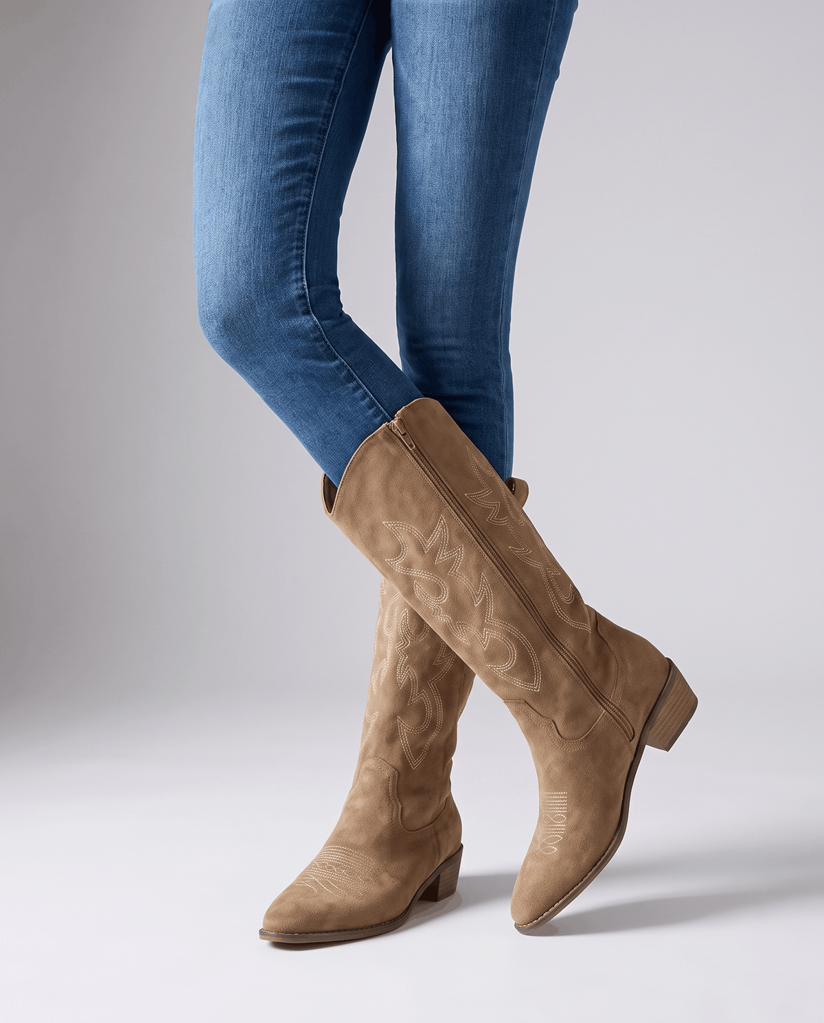 Brown embroidered boots worn standing with blue jeans tucked into the shaft