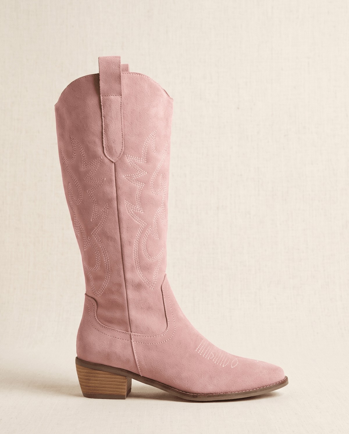 Single pink knee-high boot in side profile against a soft cream backdrop