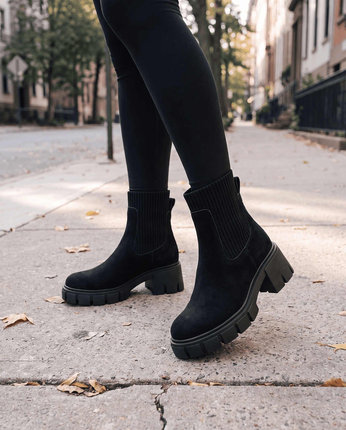 Black suede platform boots worn with leggings on a city street