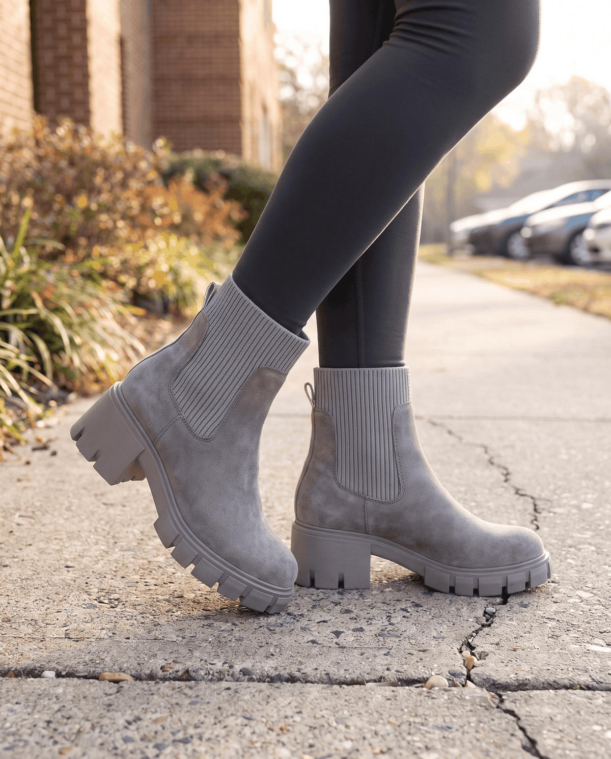 Gray suede platform boots worn with dark leggings outdoors