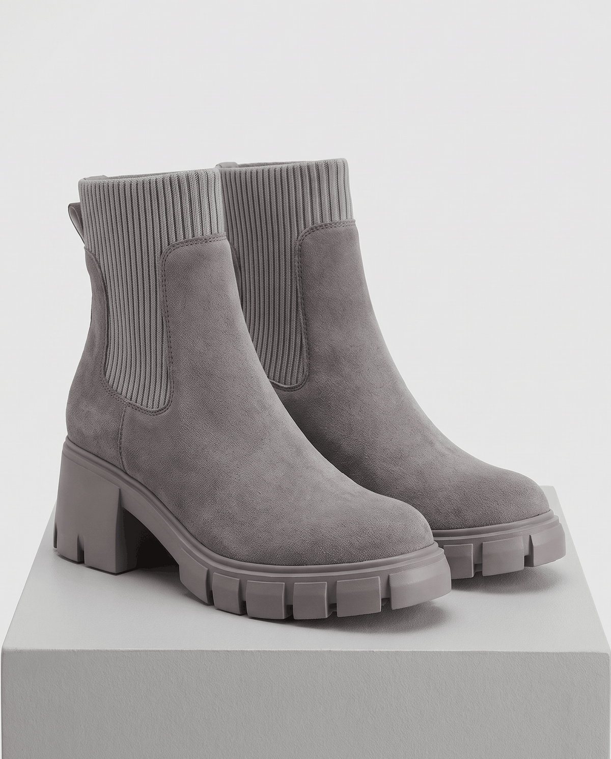 Pair of gray suede platform boots displayed on a pedestal