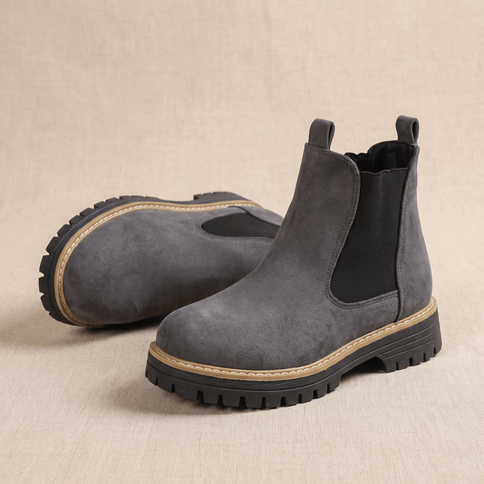 Close-up of gray suede Chelsea ankle boots worn with beige trousers.