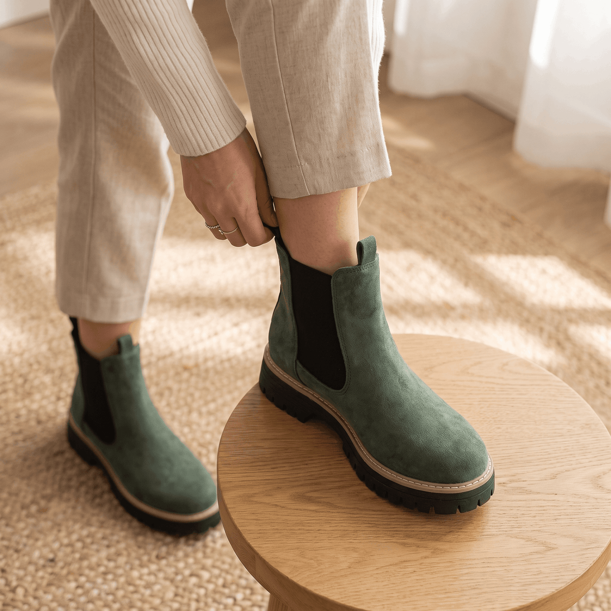 Person wearing green suede Chelsea ankle boots indoors.