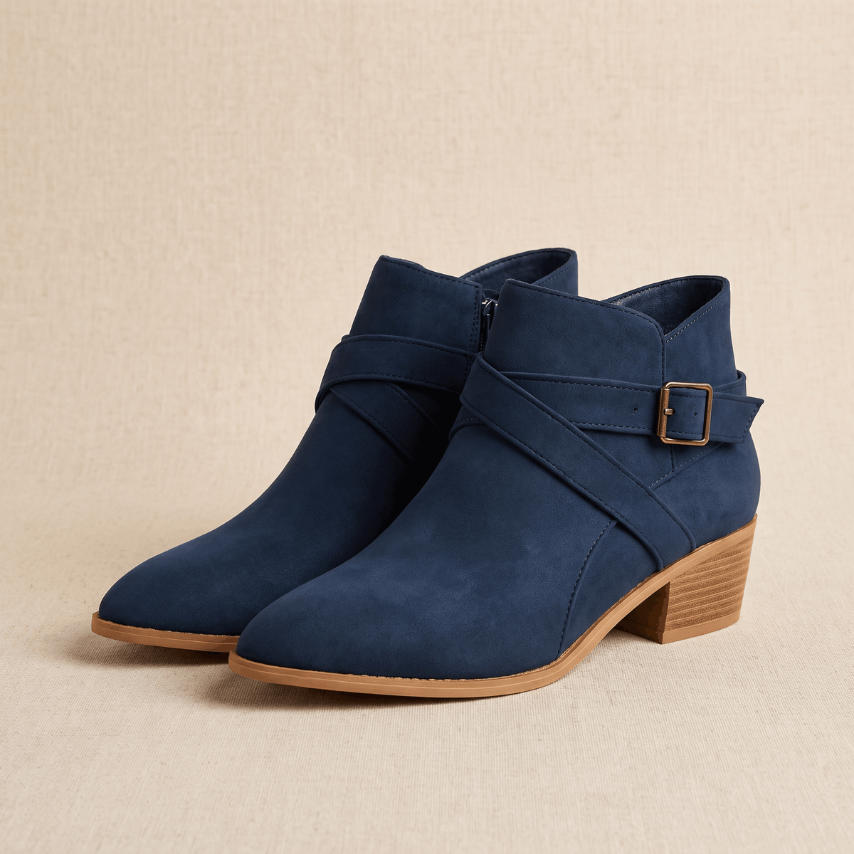 Pair of blue suede ankle boots with buckle details on a neutral background.
